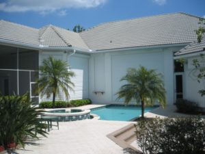 Picture of hurricane shutters installed on the back of a house, adjacent to a pool and a hot tub.