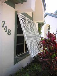 Cream and olive-green home with white Bahama shutters.