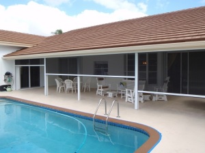 One-story home with security screens drawn over the patio.