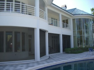 Two-story home with security screens installed on backyard patio.